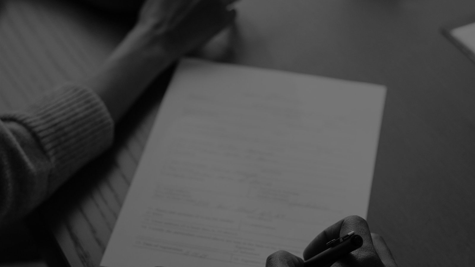 Two people signing an agreement across a table