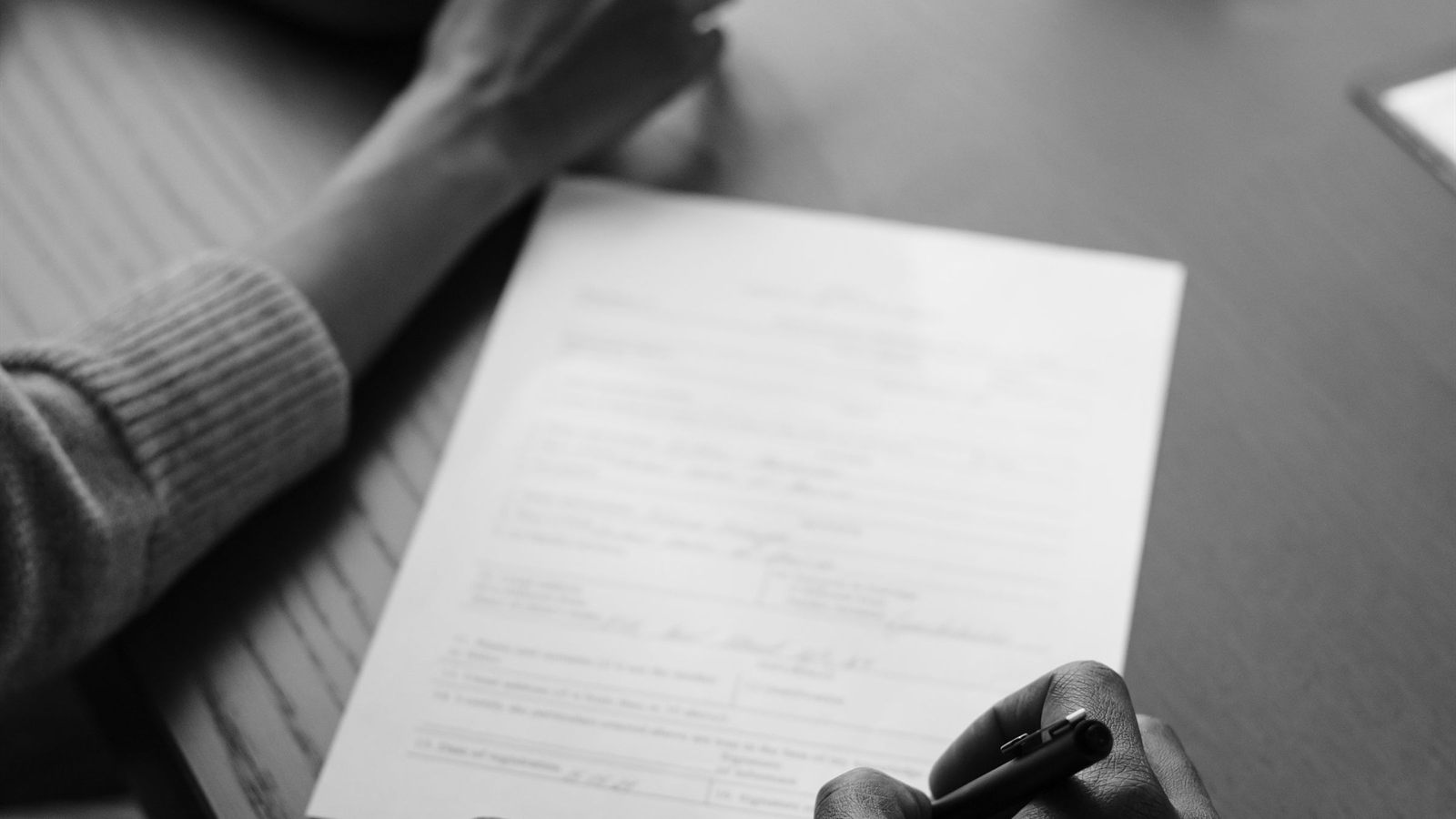 Two people signing an agreement across a table